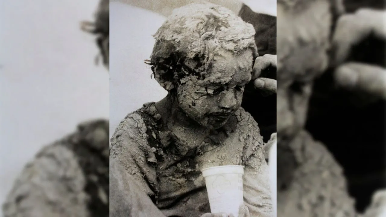 Un niño víctima de la tragedia cubierto de lodo.